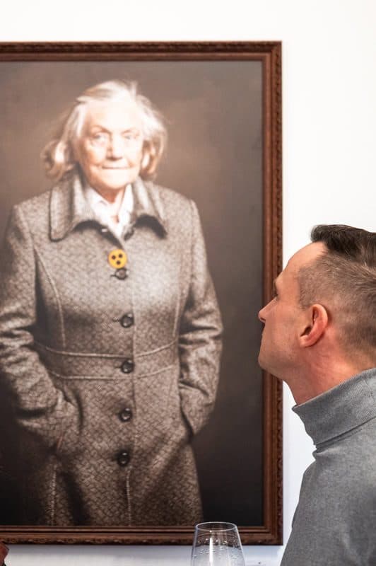 Besucher betrachtet ein großformatiges Porträt an der Galeriewand