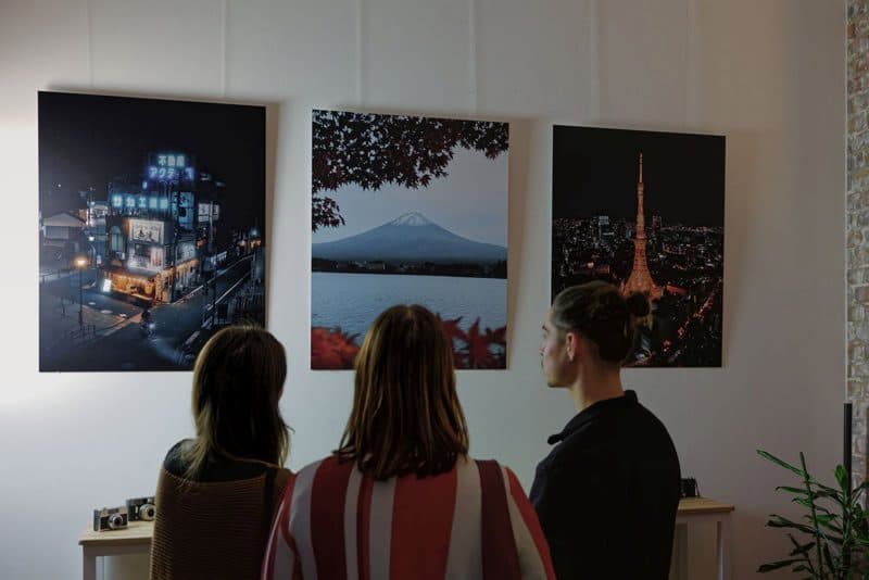 Drei Besucherinnen vor großformatigen Fotografien in der Galerie