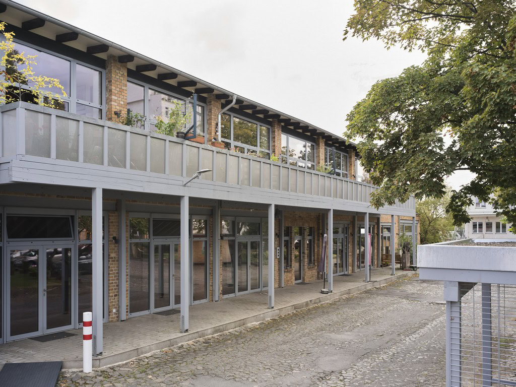 Modernes Bürogebäude mit Glasfassade und Balkon im urbanen Umfeld.