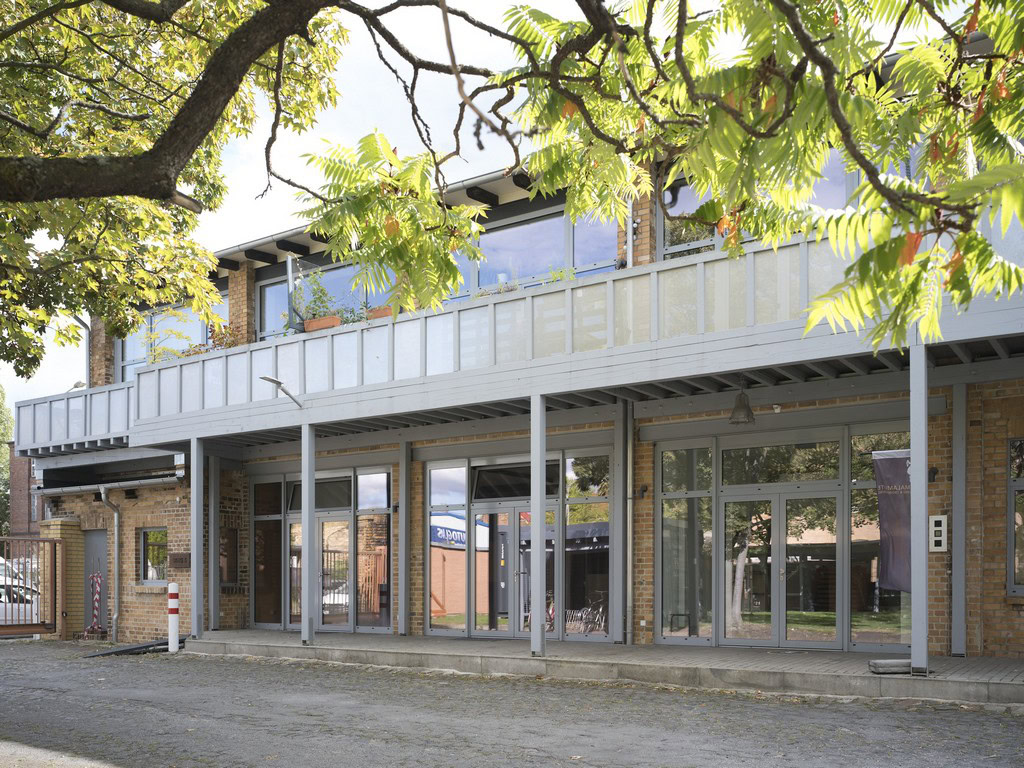 Modernes zweistöckiges Gebäude mit großen Glasfenstern und Balkon im Obergeschoss.